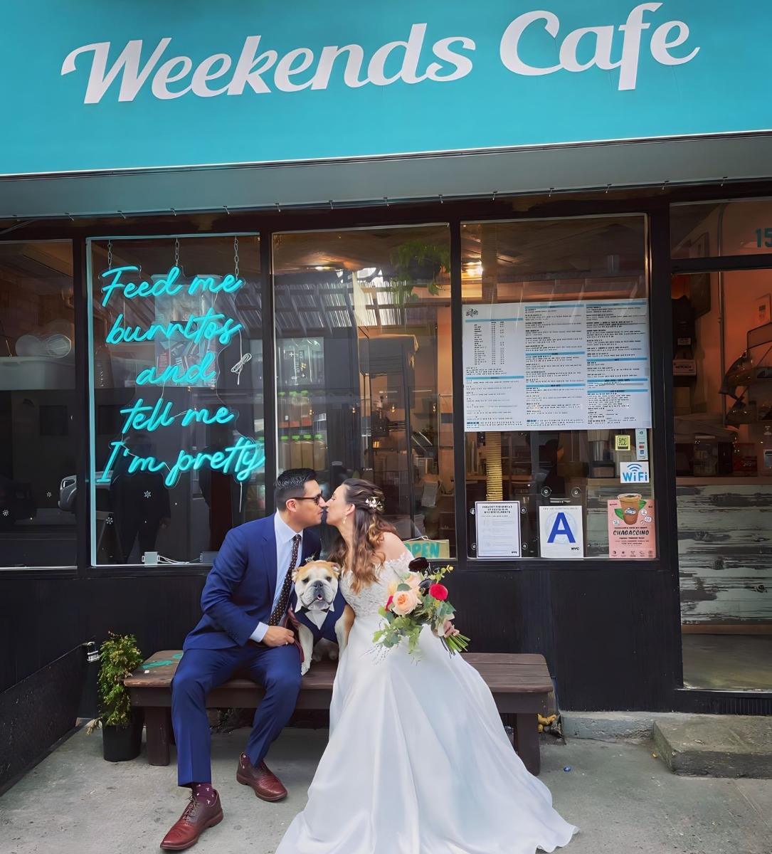 Bride and groom pose in front of a blue Custom Neon® window sign @weekendsbk cafe